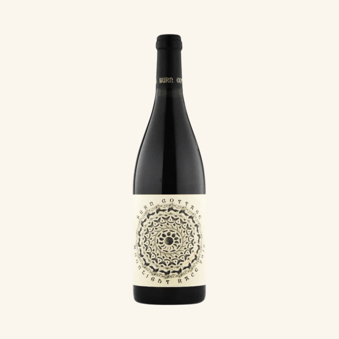 A bottle of Burn Cottage Moonlight Race Pinot Noir wine with a label featuring a detailed white geometric pattern on a dark background.