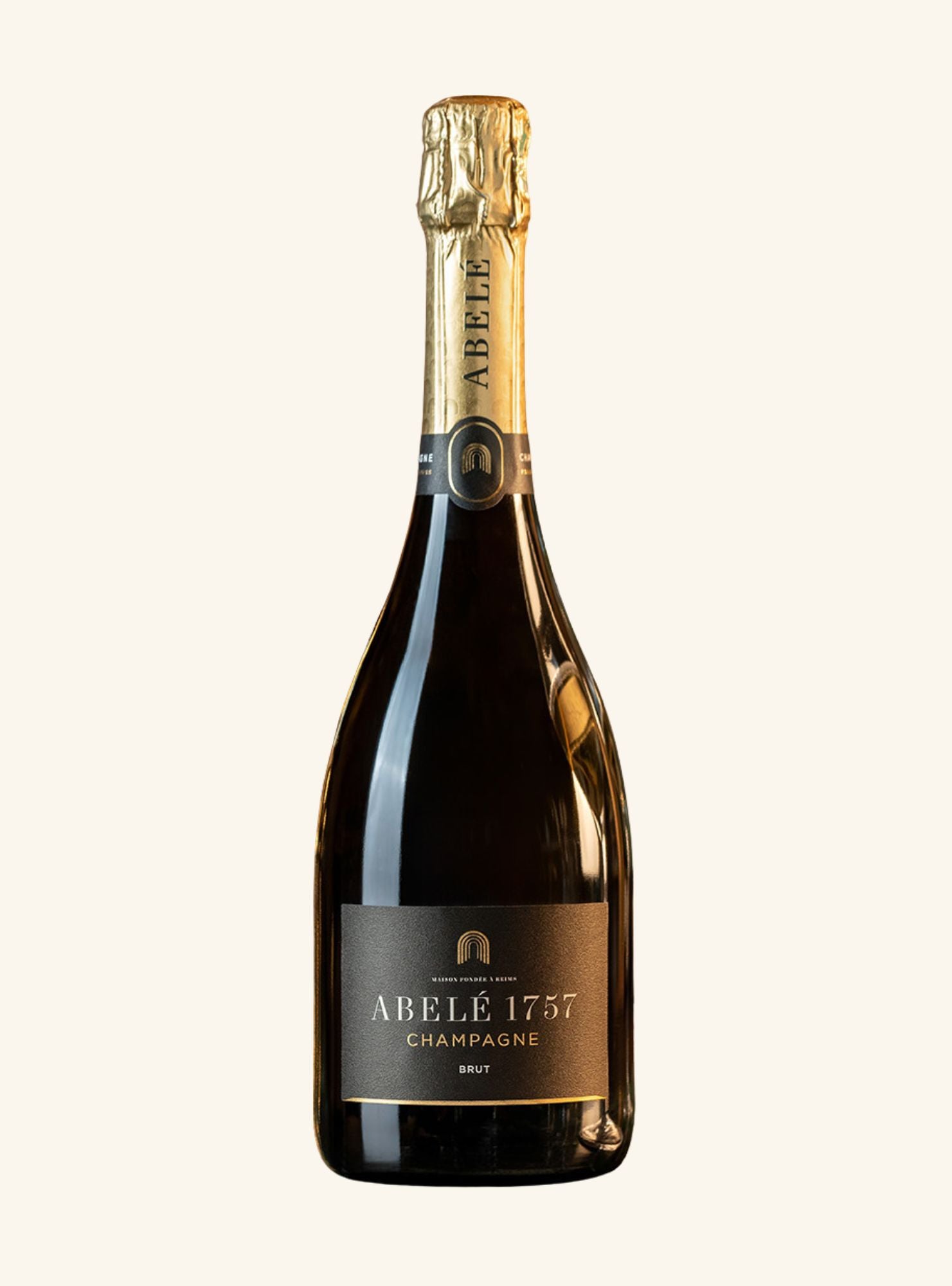 A bottle of Abelé 1757 Champagne Brut on a solid off-white background. The bottle is dark glass with a gold foil capsule and a black label with gold lettering.
