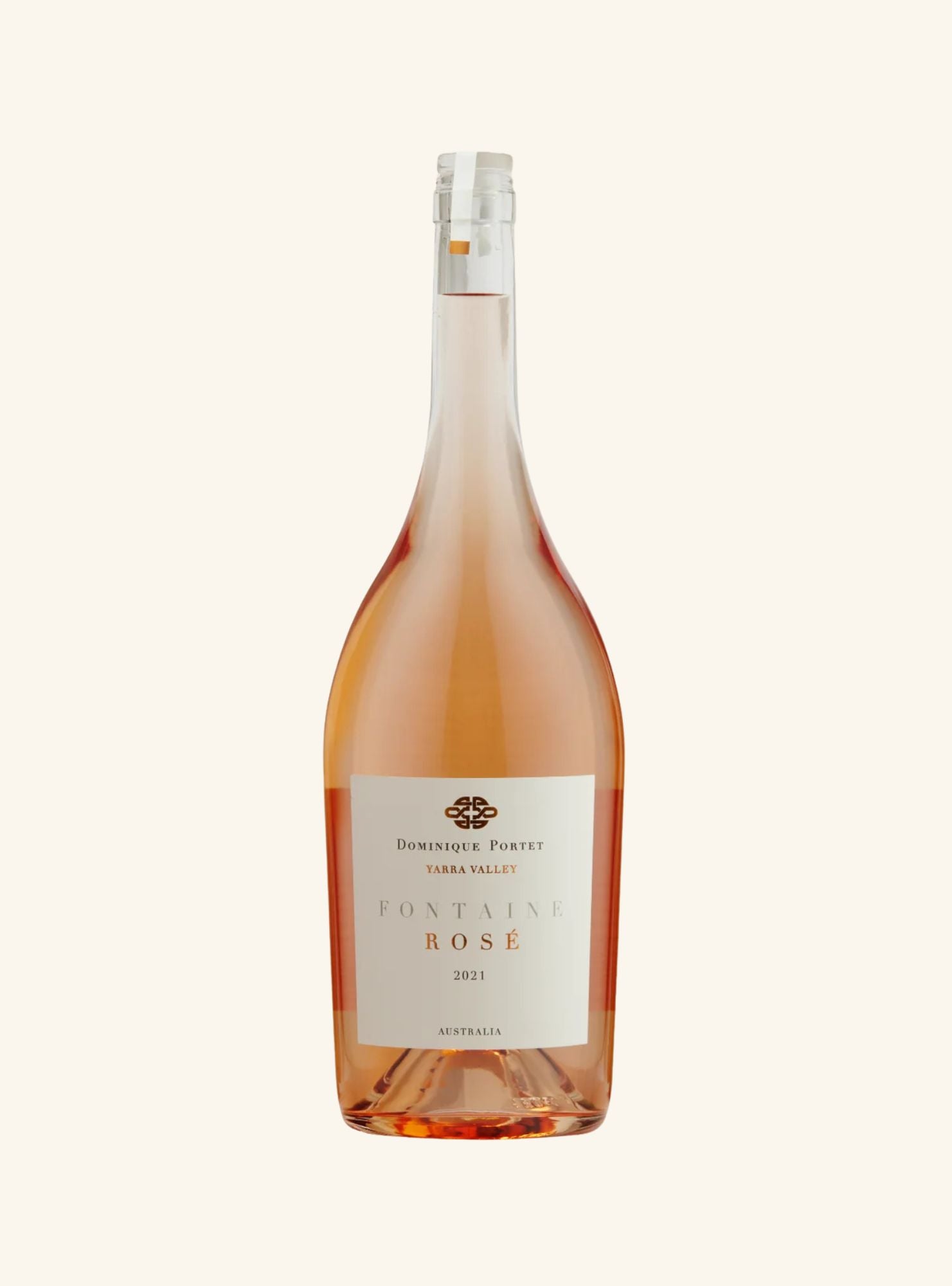 A large magnum bottle of Dominique Perret Fontaine Rose from Yarra Valley, Australia, showing the rose-colored wine inside through a clear glass bottle with a white label and silver foil, set against a solid off-white background.