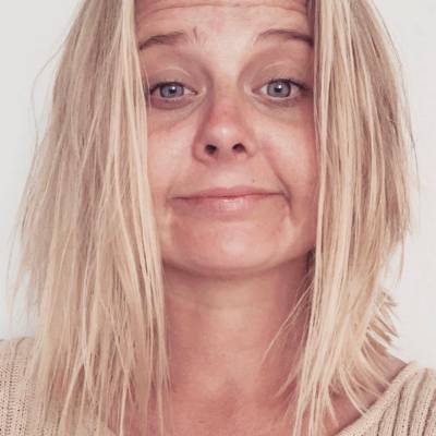 Close-up of a person with blonde hair against a plain background