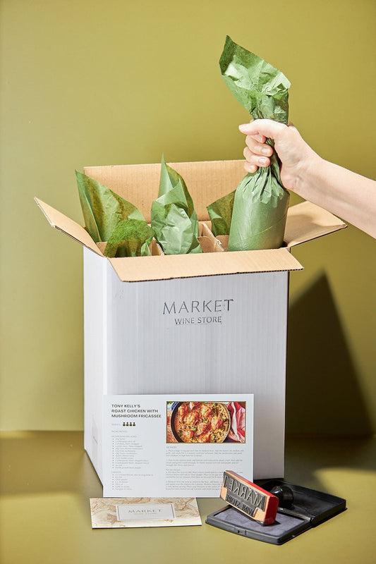 Personalised Wine Pack Market Wine Store - Hand placing wrapped bottles in stamped box with recipe card