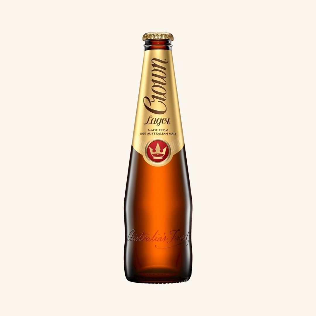 Brown beer bottle with gold label branded Crown Lager on a white background