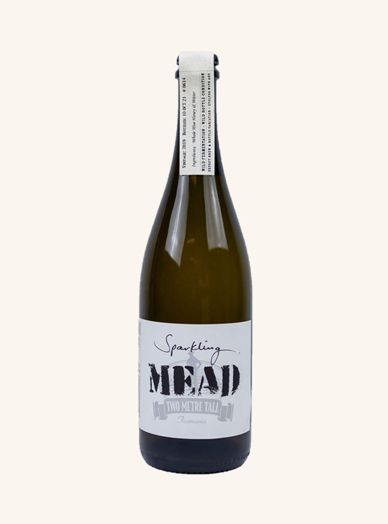 Bottle of sparkling mead by two metre tall with a white label on a white background