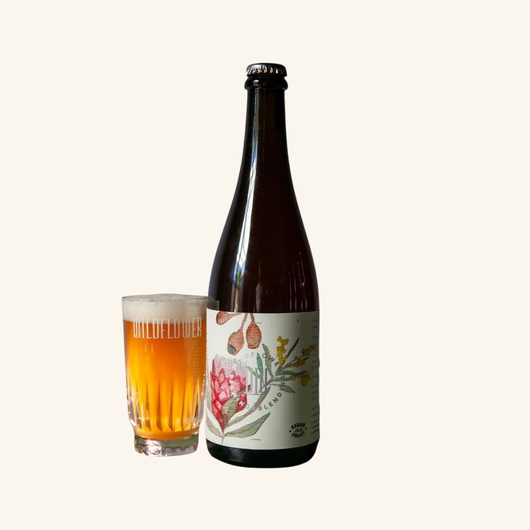 Bottle of Wildflower beer with a floral label next to a glass of beer on a white background